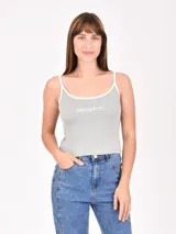 Musculosa de tejido acanalado color verde claro, con tirantes finos y ribete blanco en escote y sisas. Presenta un pequeño texto bordado en el pecho.