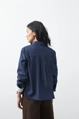 Camisa de manga larga en color azul oscuro con bordados florales en hilo blanco a lo largo de la botonadura frontal. Presenta cuello clásico y corte relajado.