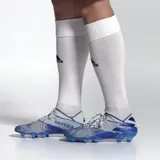 Championes de fútbol Adidas Nemeziz 19.1 FG, color blanco con rayas azules y suela azul traslúcida.