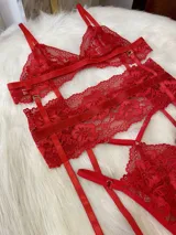 Conjunto de lencería de cuatro piezas en color rojo, confeccionado en encaje. Incluye bralette, tanga, portaligas y ligas regulables con enganches desmontables.