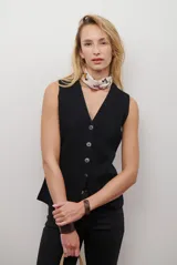 Chaleco tejido de punto en color beige, con escote en V, cierre frontal con botones oscuros y bolsillos frontales decorativos.