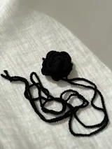 Gargantilla negra tejida a crochet con forma de flor.