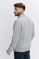 Cardigan de punto color azul marino, con cierre frontal completo, cuello alto y puños acanalados. Presenta un pequeño bordado distintivo en el pecho.
