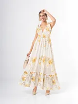 Vestido largo de estilo romántico confeccionado en tencel y lino, con fondo off white y estampa floral amarilla. Presenta escote en V, bajo busto elastizado, breteles anchos con lazos en los hombros y falda amplia con volantes y forro.