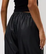 Pantalón aladín de poliuretano color negro, de corte ancho con diseño abullonado y botamangas elásticas ajustadas, con cintura elástica.
