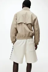 Short de felpa color beige de la marca Lotto, con cintura elástica con cordón de ajuste, bolsillos laterales y franjas laterales estampadas con el logo de la marca.