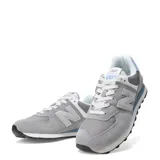 Championes urbanos New Balance modelo 574, combinando tonos de gris y celeste. Presentan una estructura de gamuza y paneles de malla técnica, con el logo N característico en los laterales y entresuela con tecnología ENCAP para mayor amortiguación.