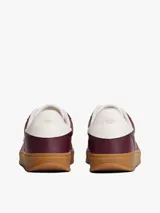 Zapatillas de corte bajo confeccionadas en piel napa brillante color bordó, con suela de goma color caramelo. Presentan insignia metálica del monograma TH en el lateral y detalle en blanco en el talón.