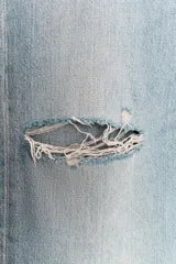 Jeans de tiro bajo, pierna ancha y largo completo, color celeste claro con efecto desgastado y rotos a la altura de las rodillas.