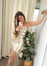 Vestido de fiesta color champagne, strapless, con abertura en la cintura y falda midi con flecos.