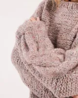 Buzo tejido a mano con lana, color rosa con motas de colores. Diseño oversized, largo entre la cintura y la cadera, con detalle de trenzas en las mangas.