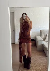 Vestido corto de cuello halter con estampado abstracto en tonos marrones y naranjas. Presenta un diseño ajustado con un detalle de nudo lateral y una caída de tela asimétrica con bordes ondulados.