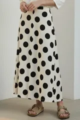 Falda midi color crudo con estampado de lunares negros, corte evasé y cintura alta.
