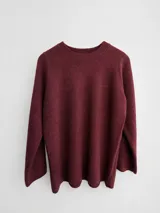 Sweater de punto de corte holgado y largo, con cuello redondo y mangas largas. Presenta un diseño minimalista y liso en color bordó.