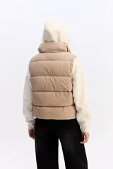 Chaleco matelaseado de color negro, con cuello alto, cierre frontal con broches y diseño acolchado con volumen.