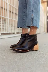 Botineta de cuero color suela, con diseño de punta fina y puntera texturizada con efecto reptil. Presenta una suela de madera clara con borde negro y cierre lateral interno.