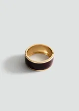 Pulsera rígida de metal dorado con esmalte negro en el centro y cierre a presión.