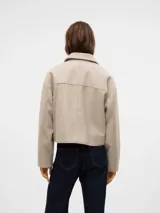 Chaqueta corta color beige con cuello con solapa y bolsillos en el pecho con cierre de botón.