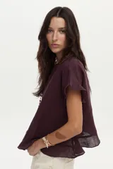 Blusa de lino color bordó, con mangas cortas adornadas con volados y diseño amplio.
