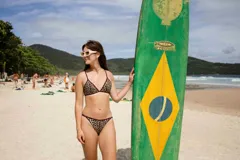 Bombacha de bikini negra con ribetes en color amarillo pastel. Presenta tiras laterales finas ajustables y una pequeña placa metálica decorativa con el nombre de la marca en la parte superior.