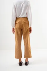 Pantalón de vestir color camel, tiro alto, corte recto y ancho, con puños doblados en el ruedo.