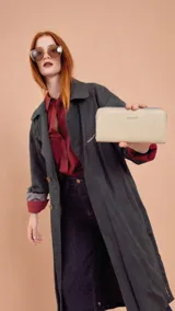 Billetera larga tipo sobre de la marca Lincoln's, confeccionada en material sintético con textura suave en color beige. Presenta un cierre perimetral metálico y el logo de la marca grabado en la parte frontal.