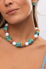 Collar corto compuesto por cuentas grandes de piedra turquesa irregular, alternadas con cuentas circulares blancas, naranjas y lilas.