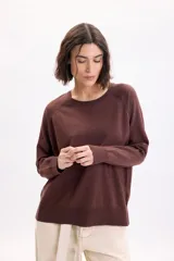 Sweater de punto fino con hilo lurex en color marrón, cuello redondo y mangas largas con hombros caídos.