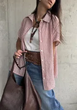 Camisa de manga corta con diseño a rayas rojas y blancas, cuello clásico y cierre frontal de botones.
