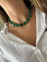 Collar corto estilo gargantilla compuesto por cuentas ovaladas de piedra verde esmeralda, separadas por pequeñas cuentas redondas plateadas.