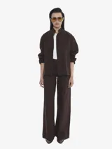 Chaqueta de algodón color marrón oscuro, con cuello mao, cierre frontal y bolsillos delanteros. Presenta un calce regular y textura suave.