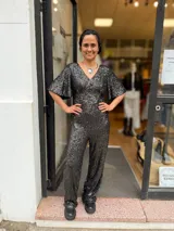 Enterito de lentejuelas color negro con escote en V, mangas cortas sueltas y pantalón largo de corte recto.