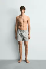 Short de baño confeccionado en tejido técnico con patrón de rayas verticales en tonos azul marino y blanco, con cintura elástica ajustable mediante cordón y bolsillos laterales.