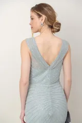 Vestido largo de tul color verde agua, enteramente bordado con lentejuelas, con escote en V cruzado y corte imperio.
