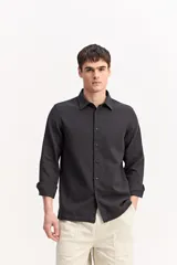 Camisa de manga larga con tejido texturado, cuello camisero y cierre frontal de botones, de corte clásico.
