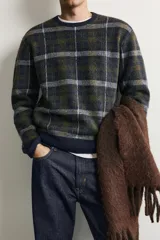 Jersey de punto con lana, de corte relajado, cuello redondo y manga larga. Presenta un diseño de cuadros en tonos oscuros con acabados en rib en cuello, puños y bajo.