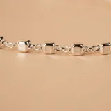 Pulsera de cadena fina de plata 925 con pequeños dijes en forma de cubos pulidos distribuidos a lo largo de la misma.