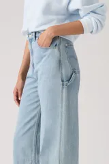 Pantalón de jean estilo carpenter con corte baggy y pierna ancha. Presenta tiro alto, bolsillos laterales y traseros, y costuras reforzadas características del diseño utilitario.