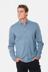 Camisa de manga larga color verde oscuro, con cuello abotonado y logo bordado en el pecho.