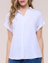 Blusa blanca de algodón y viscosa, con cuello camisero, escote en V y mangas cortas con vuelta.