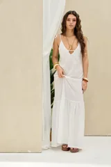Vestido largo blanco de lino, con tirantes finos para anudar en los hombros, escote en V y falda larga con volante inferior.