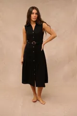 Vestido midi negro sin mangas, con cuello camisero, botonadura frontal completa, cinturón ajustable con hebilla carey y falda con volado en el ruedo.