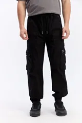 Pantalón cargo negro de corte amplio, con cintura elástica y cordón ajustable, bolsillos laterales con tapa y puños elastizados de inspiración streetwear.