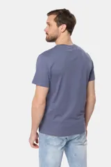 Remera de cuello redondo y manga corta, confeccionada en tejido de algodón con acabado jaspeado. Presenta un estampado frontal con temática de surf y estilo retro en tonos pasteles.