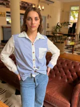 Camisa de corte clásico con diseño combinado, presenta cuerpo a rayas verticales en azul y blanco, con mangas largas y cuello en tela broderie blanca con detalles calados. Incluye bolsillo frontal en broderie y cierre central con botones.