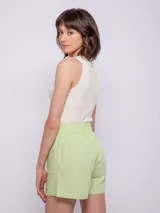 Short verde de lino con elástico en la pretina, dos botones veteados, cierre y dos bolsillos delanteros.