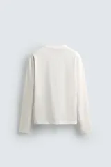 Camiseta de manga larga con corte relajado, confeccionada en algodón con acabado mercerizado y cuello redondo acabado en rib.
