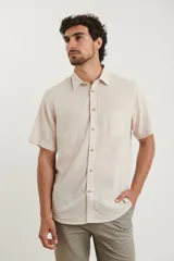 Camisa sport de manga corta, confeccionada en una mezcla de lino y algodón. Presenta cuello clásico, cierre frontal con botones de coco y un bolsillo aplicado en el pecho.