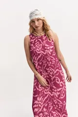 Vestido largo sin mangas, con escote redondo y silueta amplia. Presenta un estampado abstracto en tonos fucsia y rosado.