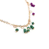 Collar dorado con cadena de eslabones y dijes colgantes de cuentas verdes y violetas.
